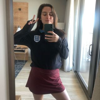 Maggie poses with a peace sign while taking a selfie in a mirror.