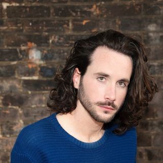 Headshot of Declan posing in front of a brick wall.